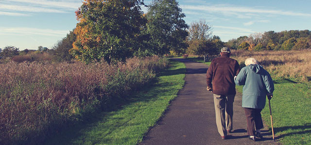 Older couple walking down a sidewalk.